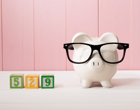 529 college savings plan theme with white piggy bank with Eyeglasses on pink wooden wall