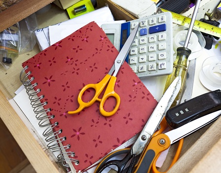 Cluttered kitchen drawer filled with a confusing jumble of everyday objects.