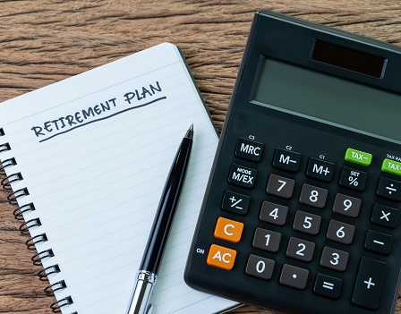 Retirement planning concept, calculator with empty notepad with pen and handwriting underline headline as Retirement Plan on wood table, plan of saving and investment for expense after retire life.