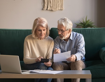 Serious mature couple calculating bills to pay, checking domestic finances, middle aged family managing, planning budget, expenses, grey haired man and woman reading bank loan documents at home