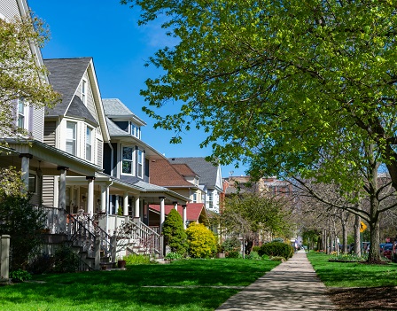 A row of old wooden homes with front lawns and a sidewalk in the North Center neighborhood of Chicago