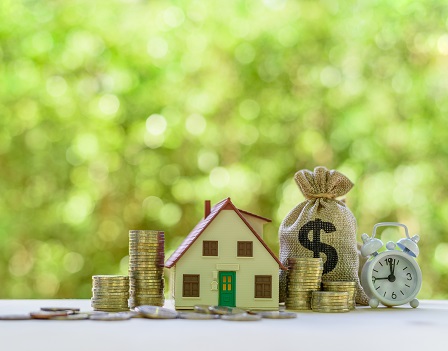 Residential real estate loan, financial concept : House model, coins, US dollar bag, white clock on a table, depicts home loan or borrowing money to buy / purchase a new home for first time homebuyer